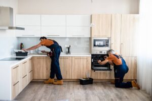 Deux professionnels installent les meubles d'une cuisine sur mesure