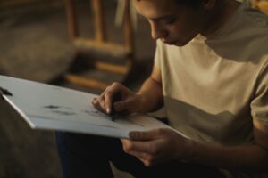 Adulte concentré s'exerçant au dessin au fusain sur un carnet de croquis dans un atelier